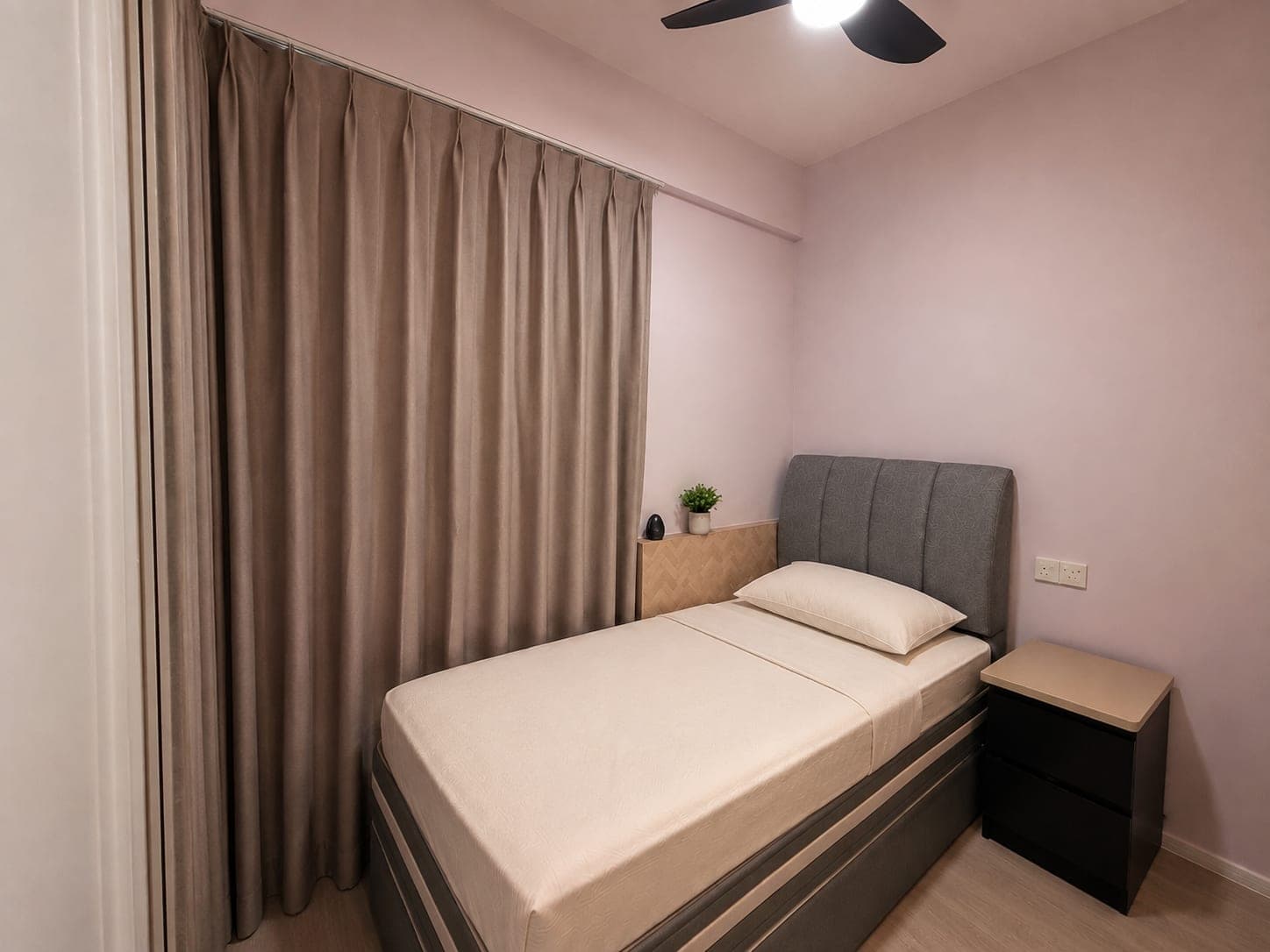 A bedroom with a casement window standing open, a curtain gathered at the left edge and a made bed against the far wall