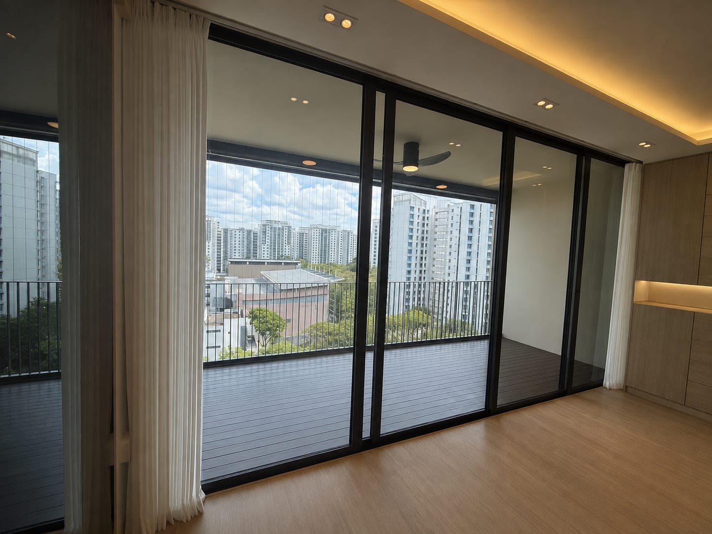 The same bedroom with a taupe curtain drawn across the entire window wall, bed and bedside table in the foreground