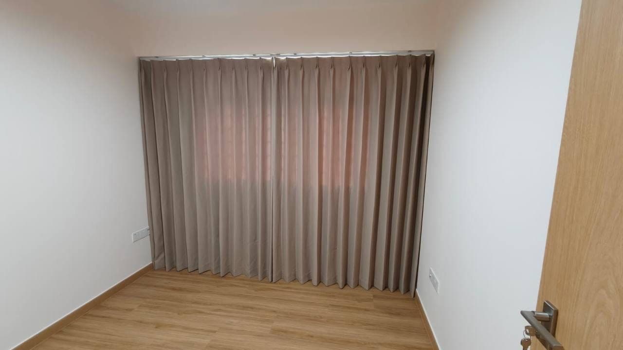 The same closed curtain photographed square on above a pale timber floor in a bare room