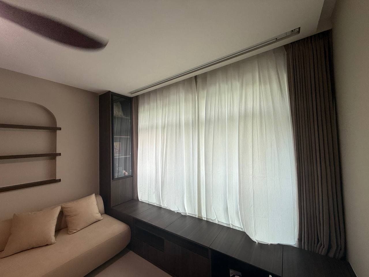 An empty room with taupe curtains at either side of an HDB window, neighbouring blocks visible outside
