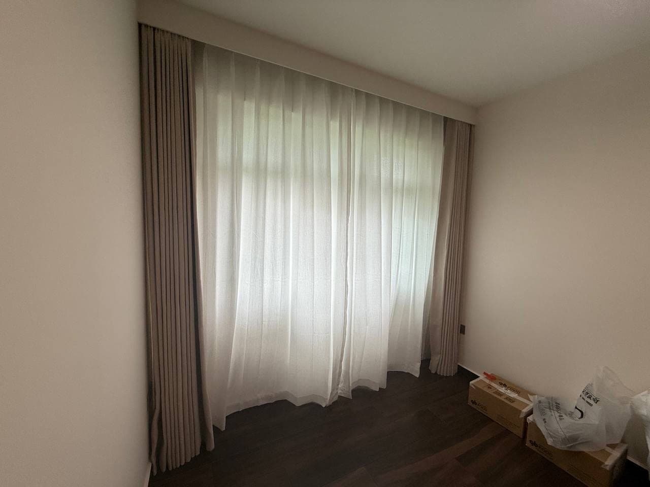 A bedroom with the taupe curtain fully closed, ceiling fan above and a mattress on the bed frame