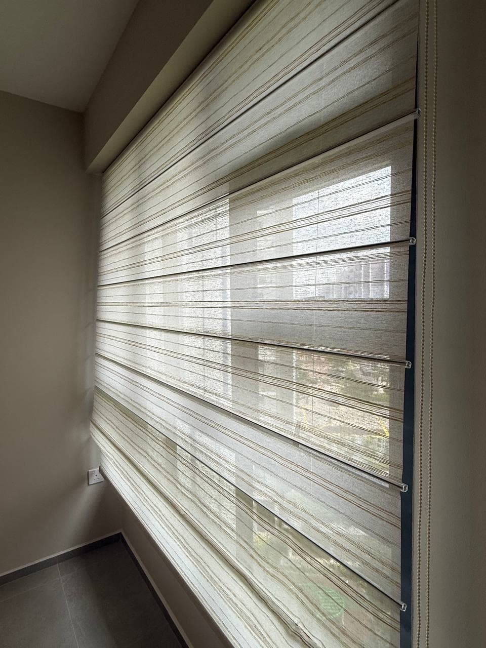 A close view of the banded blind, alternating sheer and solid horizontal strips filtering daylight