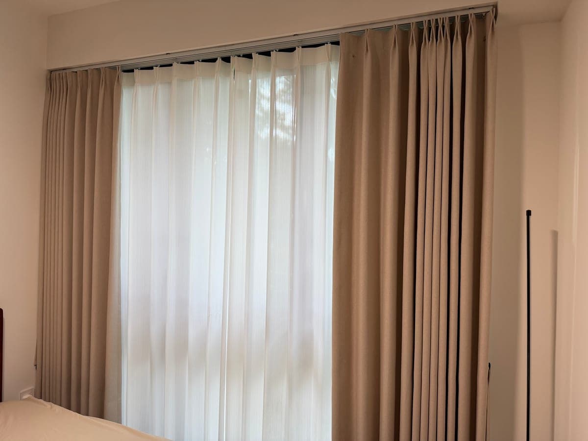 Dual-track day and night curtains in a Singapore bedroom — sheer inner layer for daytime, blackout outer layer for sleep
